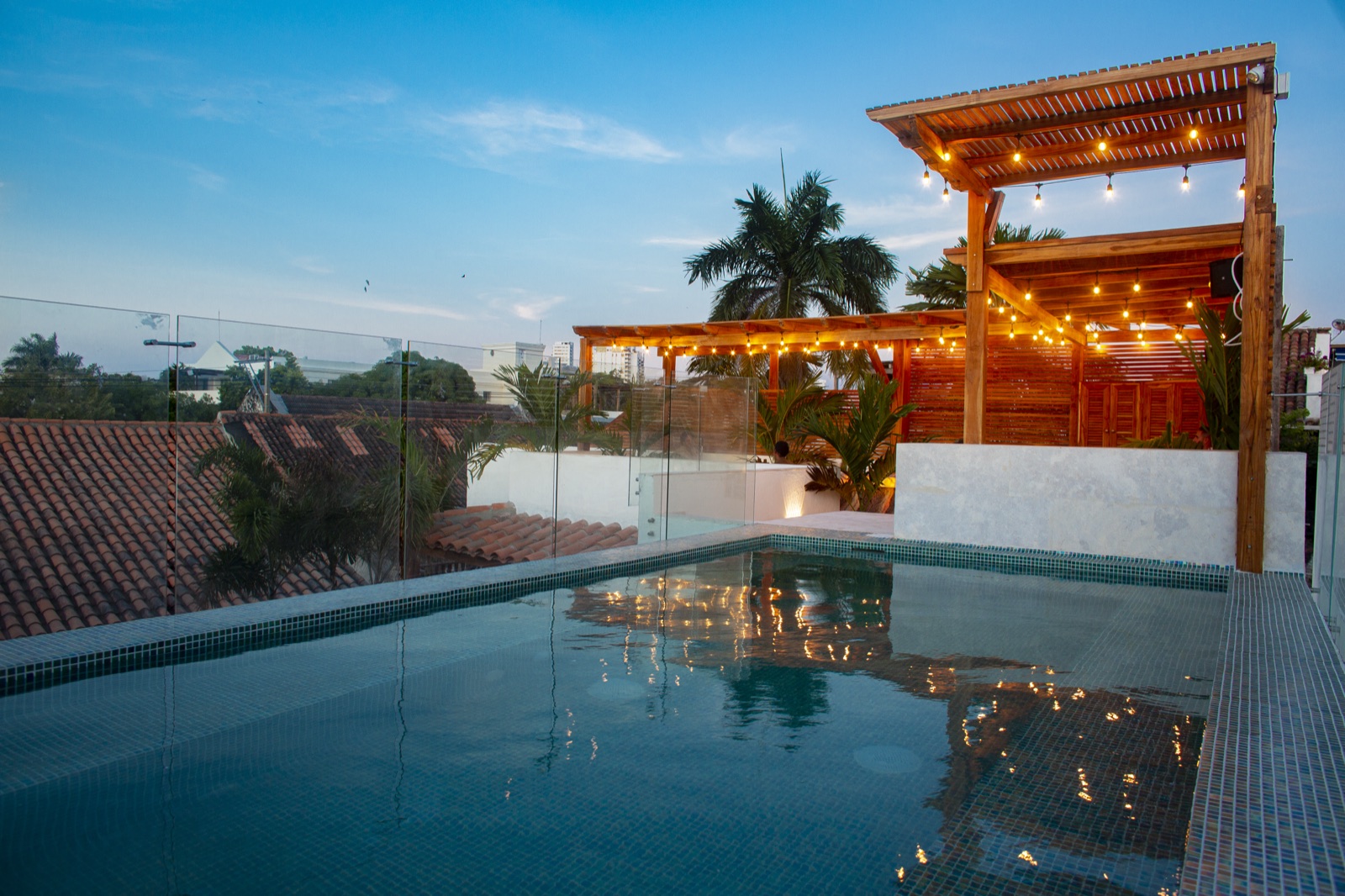 Casa Palmas rooftop plunge pool at dusk with glass railing and string lights reflecting across Cartagena's Historic Center rooftops